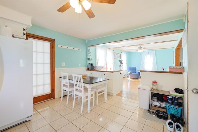 kitchen featuring freestanding refrigerator, a ceiling fan, light tile patterned flooring, and a peninsula