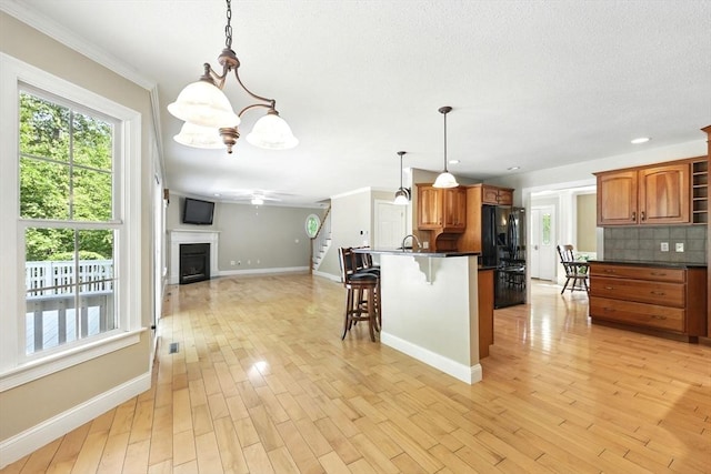 10 Tigger Ln, South Hadley, MA 01075 - kitchen with dark countertops, a breakfast bar, open floor plan, brown cabinets, and light wood-style flooring