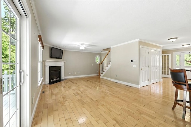 10 Tigger Ln, South Hadley, MA 01075 - unfurnished living room featuring crown molding, ceiling fan, stairway, a fireplace with flush hearth, and light wood finished floors