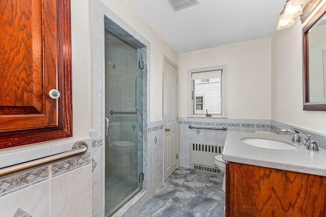 bathroom with toilet, a shower with shower door, tile walls, radiator heating unit, and vanity