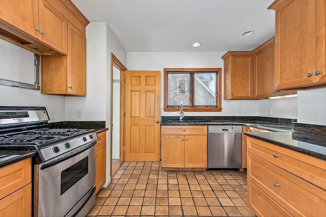 kitchen featuring dark stone countertops, sink, stainless steel appliances, and light tile patterned flooring