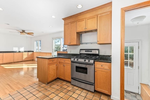 kitchen with stainless steel gas stove, light tile patterned floors, kitchen peninsula, and ceiling fan