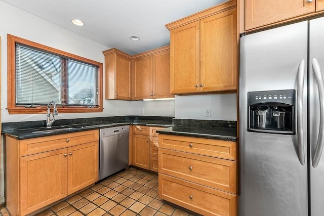 kitchen with light tile patterned floors, stainless steel appliances, sink, and dark stone countertops