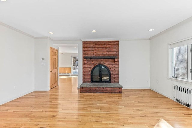 unfurnished living room with crown molding, radiator heating unit, a fireplace, and light hardwood / wood-style flooring