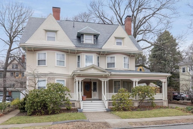 victorian house featuring a porch and a chimney