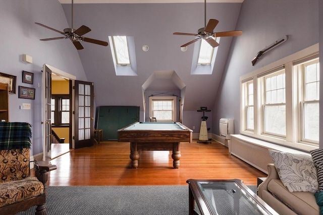 game room featuring light wood finished floors, a ceiling fan, a skylight, and high vaulted ceiling
