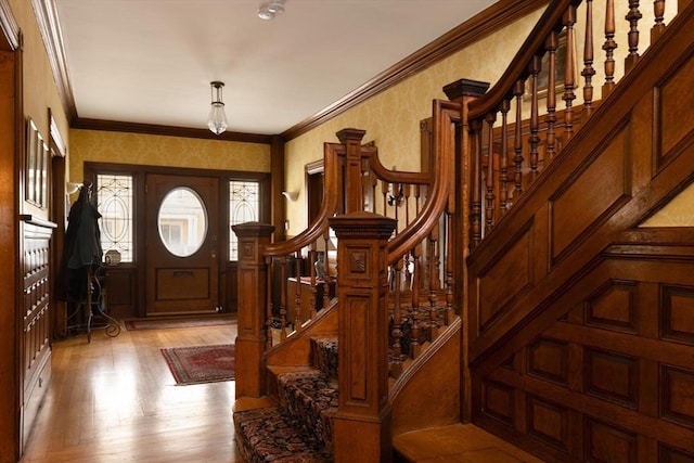 entrance foyer featuring stairs, ornamental molding, light wood finished floors, and wallpapered walls