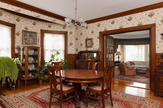 dining space with wallpapered walls, plenty of natural light, and wood finished floors