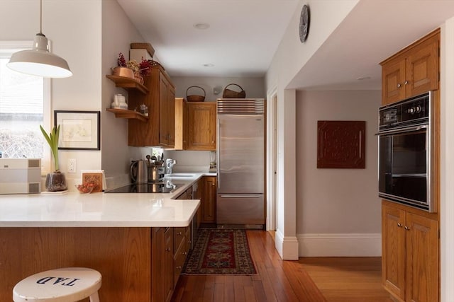 kitchen featuring brown cabinetry, open shelves, black appliances, hardwood / wood-style floors, and light countertops