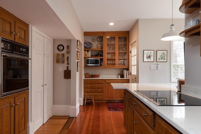 kitchen with open shelves, light countertops, wood finished floors, and black appliances
