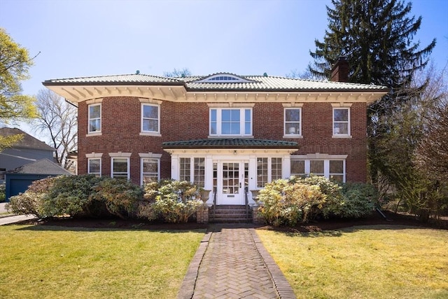 87 Crowninshield Rd, Brookline, MA 02446 - view of front facade with brick siding, a front lawn, french doors, and a chimney