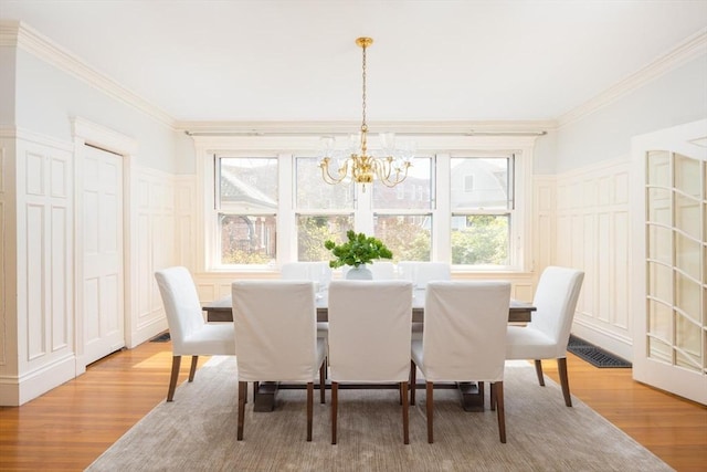 87 Crowninshield Rd, Brookline, MA 02446 - dining space with a healthy amount of sunlight, a decorative wall, wood finished floors, and a notable chandelier
