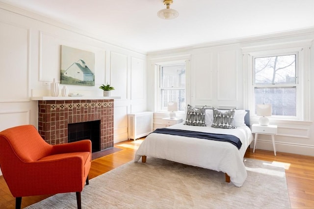 87 Crowninshield Rd, Brookline, MA 02446 - bedroom featuring radiator heating unit, light wood-style floors, a decorative wall, and a fireplace