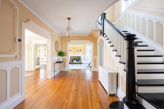 87 Crowninshield Rd, Brookline, MA 02446 - interior space with stairs, a glass covered fireplace, ornamental molding, and light wood finished floors