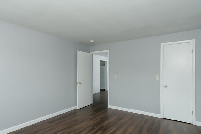 empty room featuring dark wood-style floors, baseboards, and a smoke detector
