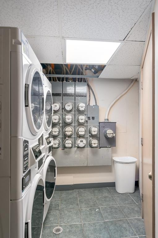 community laundry room with stacked washer and clothes dryer and tile patterned flooring