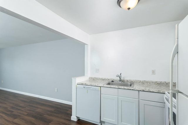 kitchen with white appliances, a sink, dark wood finished floors, light countertops, and baseboards
