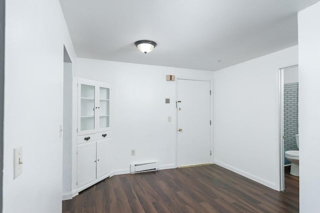 unfurnished room featuring a baseboard heating unit, dark wood-type flooring, and baseboards