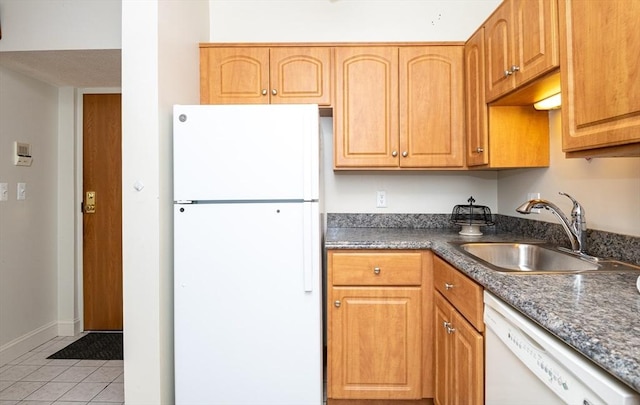 kitchen with dark stone countertops, sink, white appliances, and light tile patterned flooring