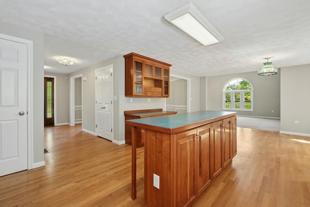 94 Old Right Rd, Ipswich, MA 01938 - kitchen with brown cabinetry, a center island, light wood-type flooring, and glass insert cabinets