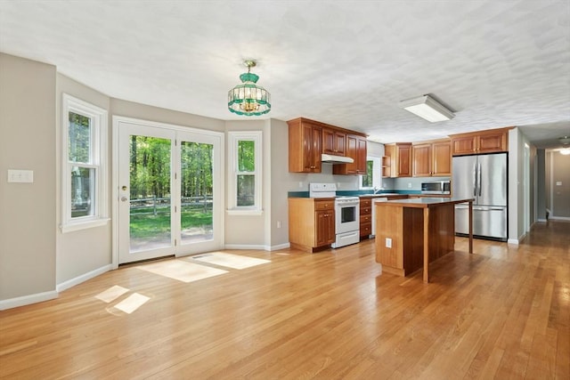 94 Old Right Rd, Ipswich, MA 01938 - kitchen with stainless steel appliances, under cabinet range hood, light wood finished floors, a center island, and brown cabinets