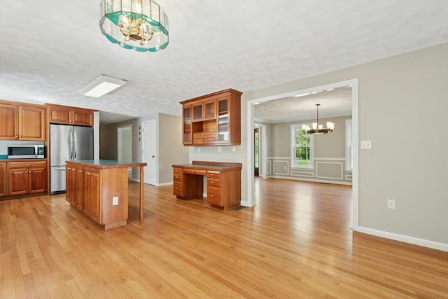 94 Old Right Rd, Ipswich, MA 01938 - kitchen with a chandelier, stainless steel appliances, light wood finished floors, brown cabinets, and a kitchen bar