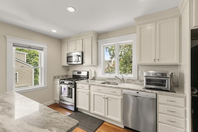 16 Field Rd Unit 16, Arlington, MA 02476 - kitchen featuring appliances with stainless steel finishes, light wood-style floors, light stone counters, recessed lighting, and white cabinets