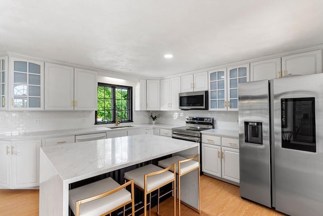 4 Blacksmith Way, Saugus, MA 01906 - kitchen featuring stainless steel appliances, a sink, light wood-style flooring, decorative backsplash, and white cabinetry