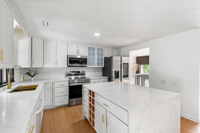 4 Blacksmith Way, Saugus, MA 01906 - kitchen with appliances with stainless steel finishes, a sink, decorative backsplash, light stone countertops, and glass insert cabinets