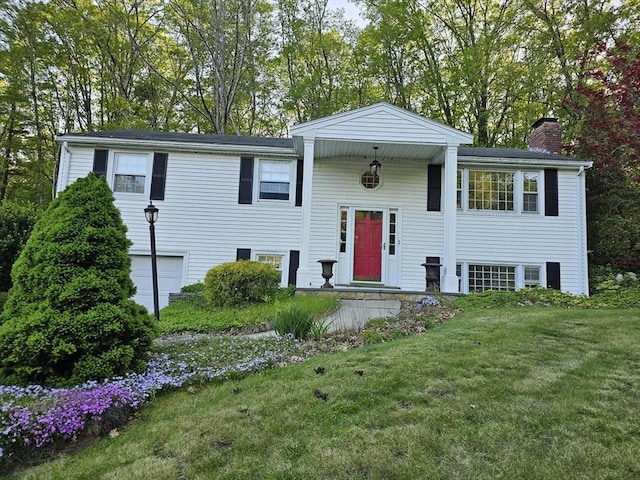 split foyer home featuring a chimney, a front yard, and a garage