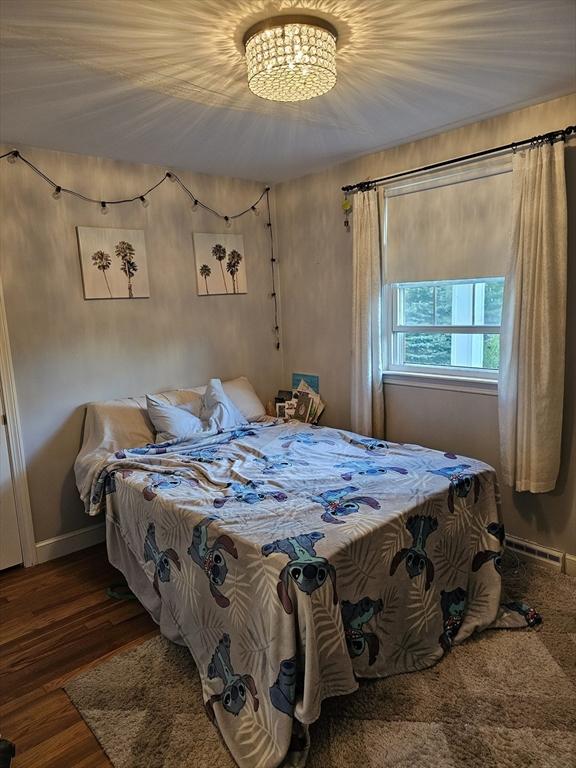 bedroom featuring baseboards, wood finished floors, and a chandelier