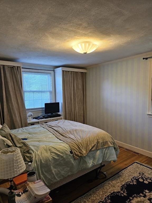 bedroom with wood finished floors, a textured ceiling, and baseboards