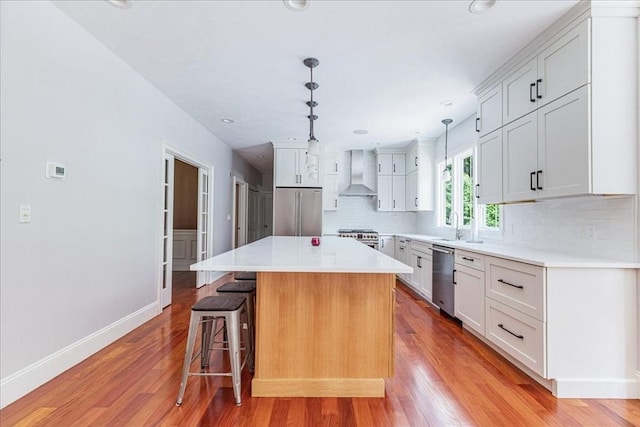138 Saddleworth Way, Middleboro, MA 02346 - kitchen featuring wall chimney range hood, appliances with stainless steel finishes, a breakfast bar, tasteful backsplash, and light wood finished floors