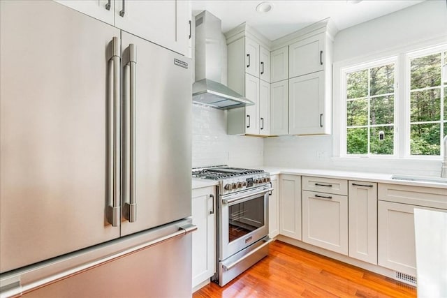 138 Saddleworth Way, Middleboro, MA 02346 - kitchen with high quality appliances, wall chimney exhaust hood, light countertops, light wood-style flooring, and decorative backsplash