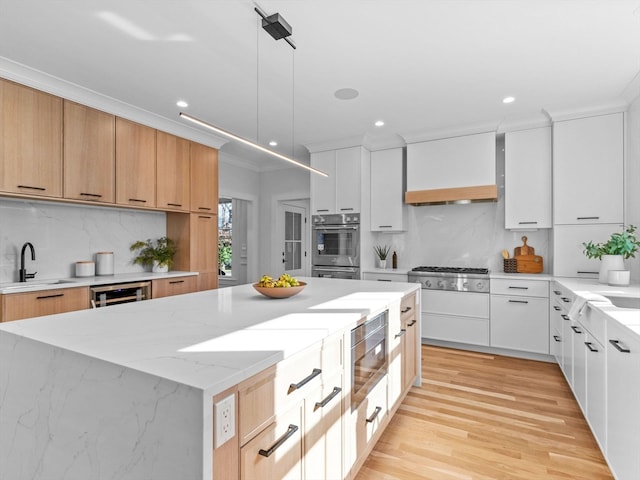 kitchen with white cabinetry, sink, a kitchen island, and light hardwood / wood-style flooring