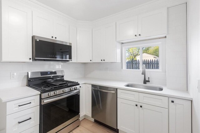 kitchen featuring light countertops, stainless steel appliances, white cabinets, and a sink