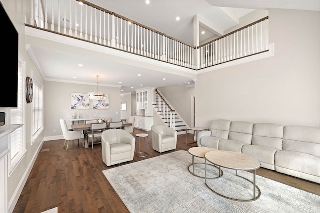 living room with a towering ceiling, ornamental molding, a chandelier, and dark hardwood / wood-style flooring