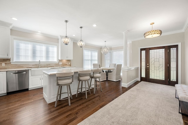 kitchen with a kitchen island, pendant lighting, stainless steel dishwasher, white cabinetry, and dark hardwood / wood-style flooring