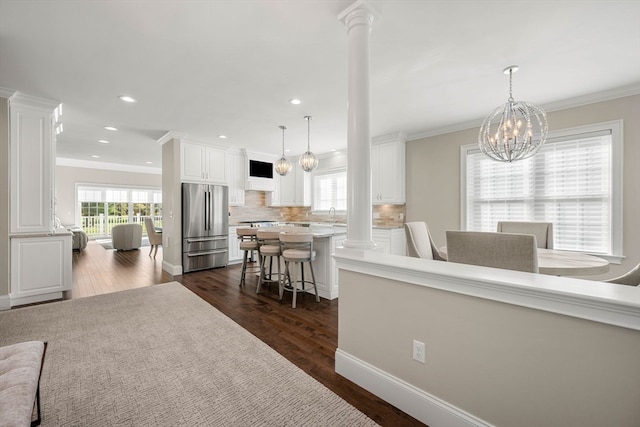 interior space featuring ornamental molding, dark hardwood / wood-style floors, a chandelier, and ornate columns