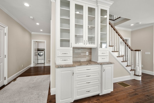 kitchen featuring washer / clothes dryer, backsplash, white cabinetry, light stone countertops, and dark wood-type flooring