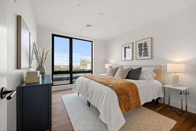 bedroom with expansive windows and dark hardwood / wood-style floors