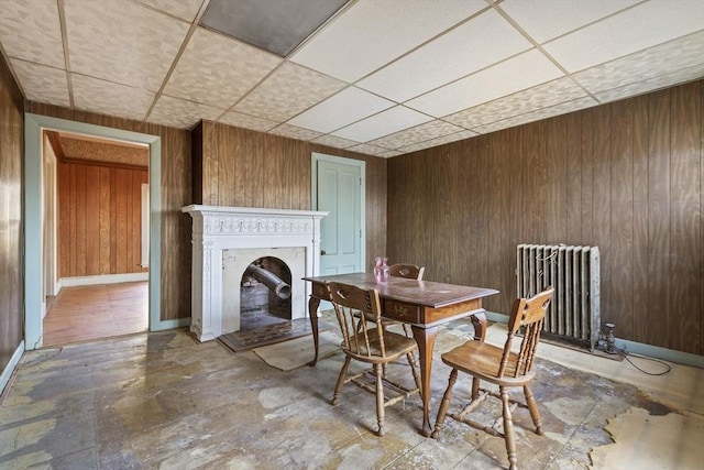 33 Burbank St, Millbury, MA 01527 - dining room featuring radiator heating unit, wood walls, a drop ceiling, a fireplace, and baseboards