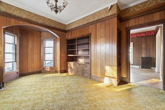 33 Burbank St, Millbury, MA 01527 - unfurnished living room featuring arched walkways, ornamental molding, a chandelier, carpet, and wood walls