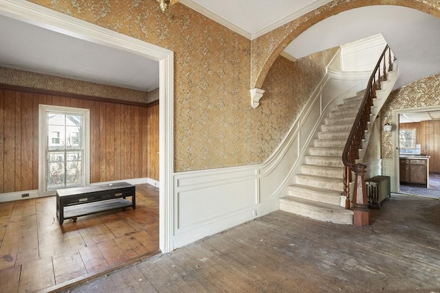 33 Burbank St, Millbury, MA 01527 - stairway featuring wood-type flooring, arched walkways, a wainscoted wall, wallpapered walls, and a decorative wall
