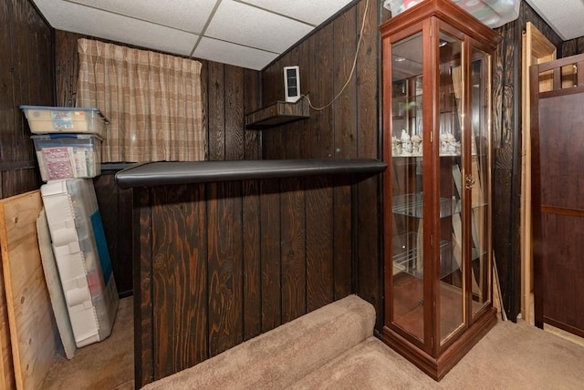 bar featuring a paneled ceiling, carpet floors, and wood walls