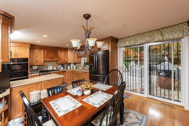 dining space featuring sink, a notable chandelier, and light hardwood / wood-style flooring