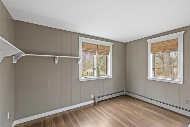 interior space with wood finished floors, baseboard heating, and plenty of natural light