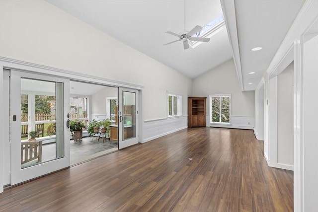 unfurnished living room featuring a wainscoted wall, high vaulted ceiling, a decorative wall, a ceiling fan, and dark wood-type flooring