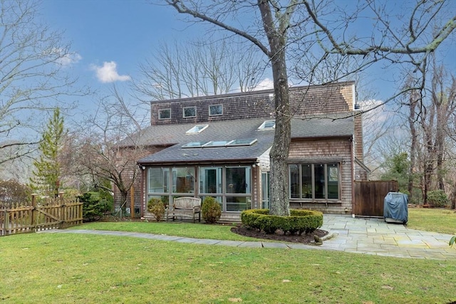 rear view of house with a lawn, a sunroom, fence, and a patio area