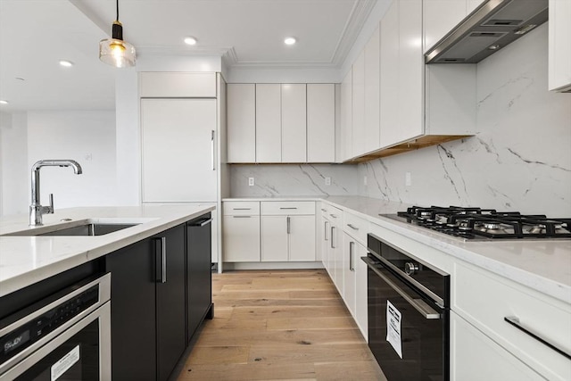 kitchen featuring oven, a sink, stainless steel gas stovetop, wall chimney exhaust hood, and white cabinets